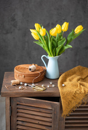 There are yellow tulips and sewing objects on the tableの写真素材