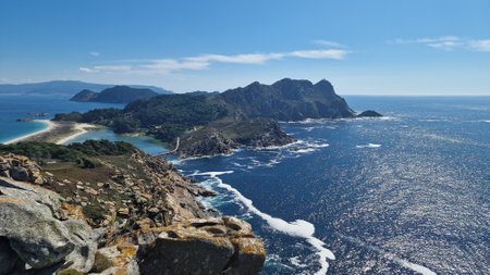 Blurred coastal landscape with rocky shore, turquoise ocean, and clear blue sky on a sunny day.