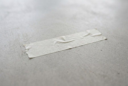 Minimalist industrial background with paper adhesive tape on rough concrete. Textured surface with wrinkles on tape creates authentic look for design, construction mockups, or artistic text inserts and layouts