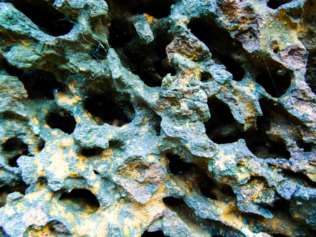 Rock with many holes and colors worn on it with black holesの写真素材