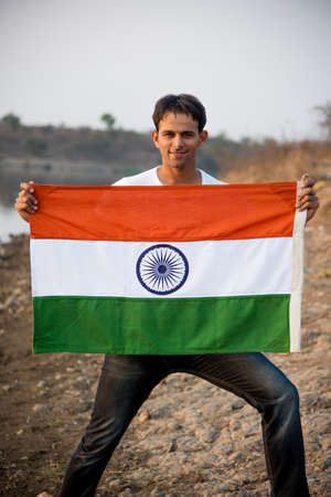indian young man holding and waving indian flag, conceptual image for republic day or independence...