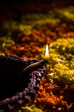 Traditional diya or oil lamp lit on colorful rangoli made up of marigold flower petal, on the festival of lights called diwali or deepawali, selective focusの写真素材