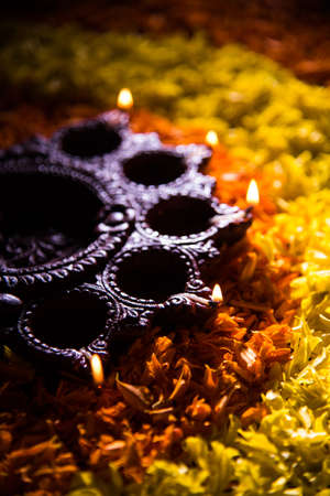 Traditional diya or oil lamp lit on colorful rangoli made up of marigold flower petal, on the festival of lights called diwali or deepawali, selective focusの写真素材