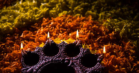 Traditional diya or oil lamp lit on colorful rangoli made up of marigold flower petal, on the festival of lights called diwali or deepawali, selective focusの写真素材