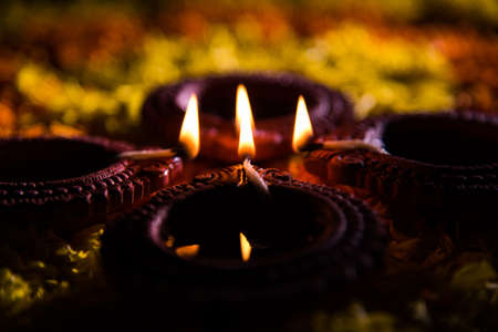 Traditional diya or oil lamp lit on colorful rangoli made up of marigold flower petal, on the...