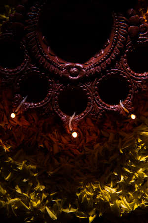 Traditional diya or oil lamp lit on colorful rangoli made up of marigold flower petal, on the...