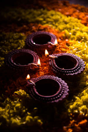 Traditional diya or oil lamp lit on colorful rangoli made up of marigold flower petal, on the festival of lights called diwali or deepawali, selective focusの写真素材