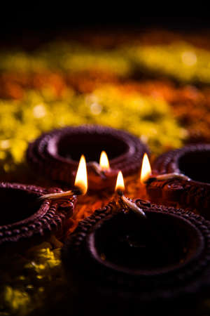 Traditional diya or oil lamp lit on colorful rangoli made up of marigold flower petal, on the festival of lights called diwali or deepawali, selective focusの写真素材