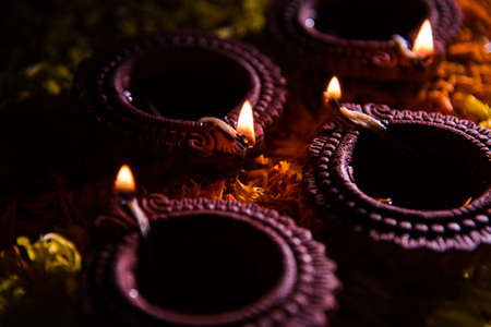 Traditional diya or oil lamp lit on colorful rangoli made up of marigold flower petal, on the festival of lights called diwali or deepawali, selective focusの写真素材