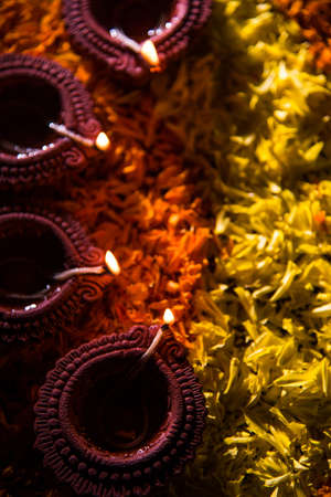 Traditional diya or oil lamp lit on colorful rangoli made up of marigold flower petal, on the festival of lights called diwali or deepawali, selective focusの写真素材