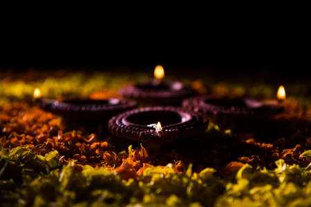 Traditional diya or oil lamp lit on colorful rangoli made up of marigold flower petal, on the festival of lights called diwali or deepawali, selective focusの写真素材