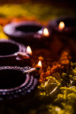 Traditional diya or oil lamp lit on colorful rangoli made up of marigold flower petal, on the festival of lights called diwali or deepawali, selective focusの写真素材