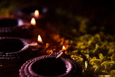Traditional diya or oil lamp lit on colorful rangoli made up of marigold flower petal, on the...