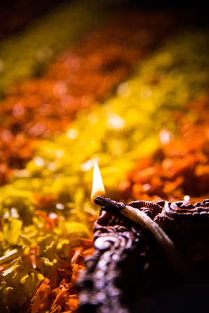Traditional diya or oil lamp lit on colorful rangoli made up of marigold flower petal, on the...