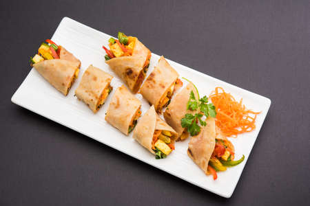 Indian popular snack food called Vegetable spring rolls or veg roll or veg franky or veg wrap made using paneer or cottage cheese and vegetables wrapped inside paratha/chapati/roti with tomato ketchup.の写真素材