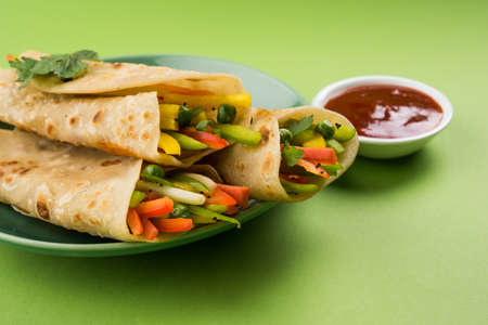 Indian popular snack food called Vegetable spring rolls or veg roll or veg franky or veg wrap made using paneer or cottage cheese and vegetables wrapped inside paratha/chapati/roti with tomato ketchup.の写真素材
