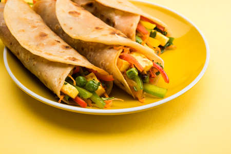 Indian popular snack food called Vegetable spring rolls or veg roll or veg franky or veg wrap made using paneer or cottage cheese and vegetables wrapped inside paratha/chapati/roti with tomato ketchup.の写真素材