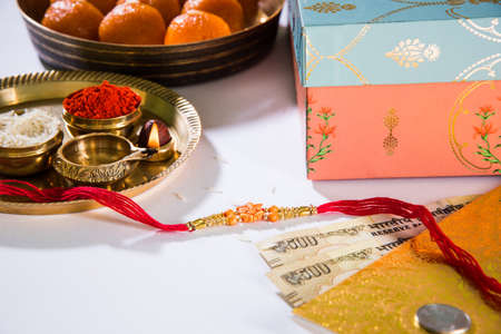 Rakhi gifts,  diya in a puja thali, indian currency notes, envelope and sweet motichur ladduの写真素材