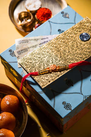 Rakhi gifts,  diya in a puja thali, indian currency notes, envelope and sweet motichur ladduの写真素材