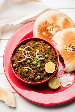 Indian Masala Kheema Pav or khima or Dry Spicy Minced Meat usually served with indian flat bread called kulcha/roti/chapati, garnished with green peas. Selective focusの写真素材