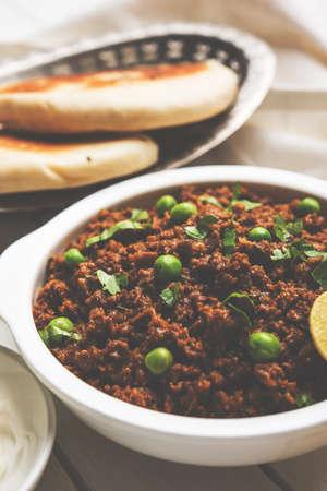 Indian Masala Kheema Pav or khima or Dry Spicy Minced Meat usually served with indian flat bread called kulcha/roti/chapati, garnished with green peas. Selective focusの写真素材