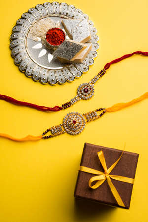 Raksha Bandhan greeting - Rakhi and gift with sweet kaju katli or mithai and rice grains & kumkum in a decorative plate. Traditional Indian wrist band is a symbol of love between Brothers and Sistersの写真素材