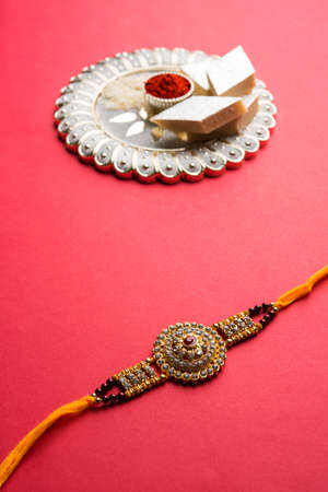 Raksha Bandhan greeting - Rakhi and gift with sweet kaju katli or mithai and rice grains & kumkum in...