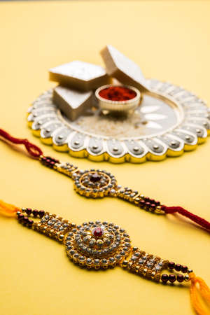 Raksha Bandhan greeting - Rakhi and gift with sweet kaju katli or mithai and rice grains & kumkum in a decorative plate. Traditional Indian wrist band is a symbol of love between Brothers and Sistersの写真素材