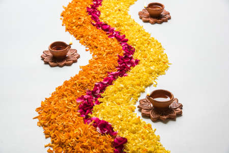 flower rangoli for Diwali or pongal made using marigold or zendu flowers and red rose petals over...