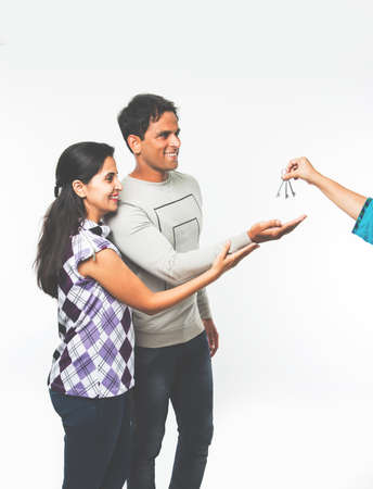 stock photo showing Indian couple who just rented or purchased new home or car. Man and woman are happy to receive keys for newly rented apartment or carの写真素材