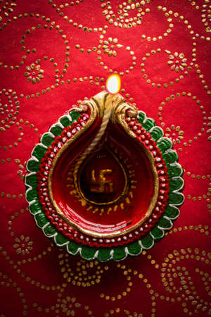 stock photo of beautiful diwali diya, isolated over decorative background, moody lighting and selective focusの写真素材