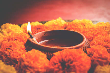 flower rangoli for Diwali or pongal or onam made using marigold or zendu flowers and red rose petals over white background with diwali diya in the middle, selective focusの写真素材