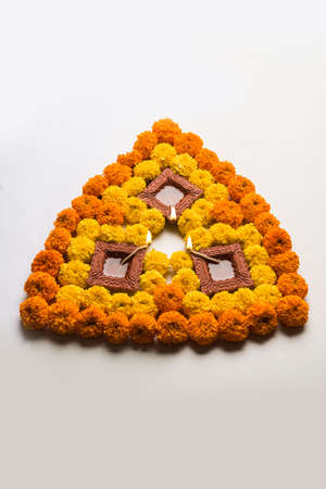 flower rangoli for Diwali or pongal or onam made using marigold or zendu flowers and red rose petals over white background with diwali diya in the middle, selective focusの写真素材