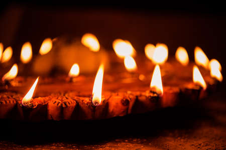Stock Photo of an illuminated terra-cotta Diwali lamp or Diya with detailed artwork on it. on a moody background and selective focusの写真素材