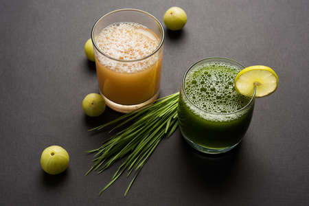 Ayurvedic or medicinal Wheat grass juice with lemon slice and Amla Juice or Avla drink in glass,...