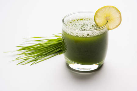 Ayurvedic or medicinal Wheat grass juice with lemon slice in glass, selective focusの写真素材