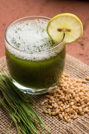Ayurvedic or medicinal Wheat grass juice with lemon slice in glass, selective focusの写真素材