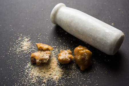 Asafoetida cake and powder or Hing or Heeng which is an important ingredient in Indian food recipes with big wooden spoon and mortar, selective focusの写真素材