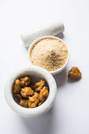 Asafoetida cake and powder or Hing or Heeng which is an important ingredient in Indian food recipes with big wooden spoon and mortar, selective focusの写真素材