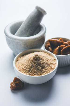 Asafoetida cake and powder or Hing or Heeng which is an important ingredient in Indian food recipes with big wooden spoon and mortar, selective focusの写真素材