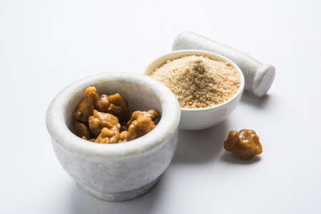 Asafoetida cake and powder or Hing or Heeng which is an important ingredient in Indian food recipes with big wooden spoon and mortar, selective focusの写真素材