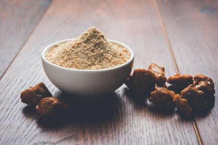 Asafoetida cake and powder or Hing or Heeng which is an important ingredient in Indian food recipes with big wooden spoon and mortar, selective focusの写真素材