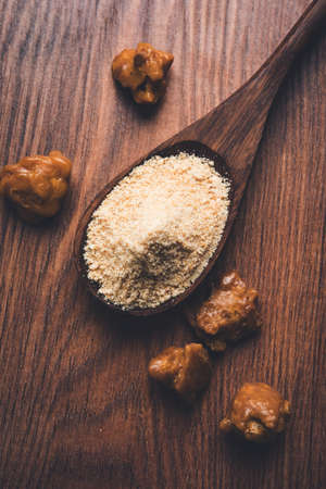 Asafoetida cake and powder or Hing or Heeng which is an important ingredient in Indian food recipes with big wooden spoon and mortar, selective focusの写真素材