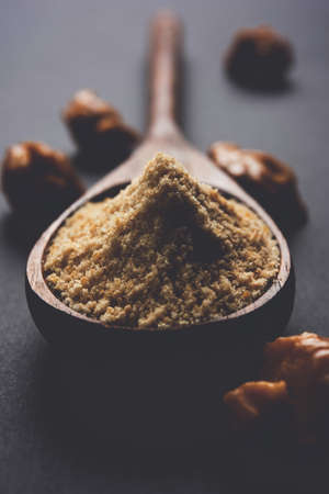 Asafoetida cake and powder or Hing or Heeng which is an important ingredient in Indian food recipes with big wooden spoon and mortar, selective focusの写真素材