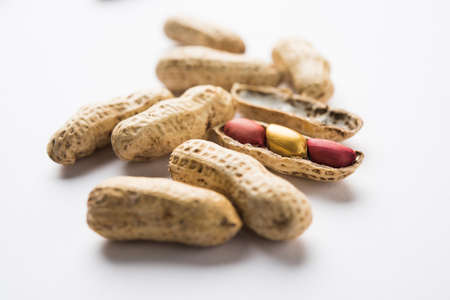 Concept of individuality, luck,value,exclusivity and better choice. Golden peanut or ground nut, standing out amongst normal peanuts, over black or white backgroundの写真素材