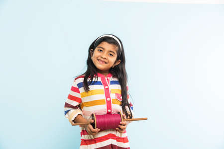 Kite or Patang flying in India, cute and happy little indian girl/female child holding chakri or...