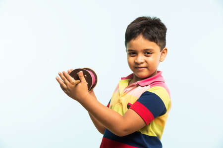 Kite or Patang flying in India, cute and happy little indian boy/kid holding chakri or wooden spindal and standing over blue background on Makar Sankranti Festivalの写真素材