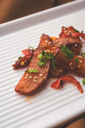 honey chilli potato or Potato wedges, popular Indian-Chinese starter recipe, garnished with sesame and onion. selective focusの写真素材