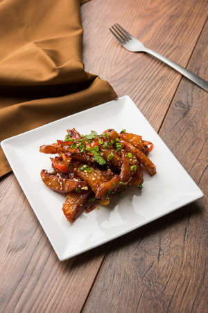 honey chilli potato or Potato wedges, popular Indian-Chinese starter recipe, garnished with sesame and onion. selective focusの写真素材
