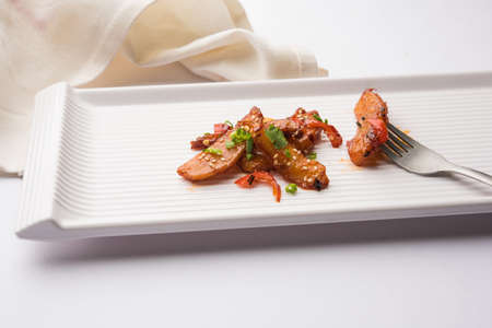 honey chilli potato or Potato wedges, popular Indian-Chinese starter recipe, garnished with sesame and onion. selective focusの写真素材